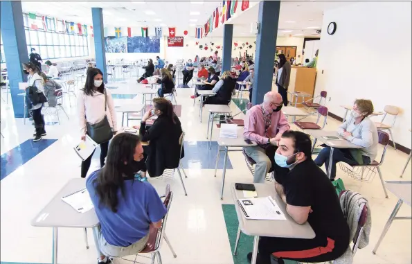  ?? Christian Abraham / Hearst Connecticu­t Media ?? Teachers and staff from Monroe’s school system wait the mandatory 15 minutes to monitor for reactions after receiving the COVID-19 vaccine during a closed vaccine clinic for Monroe school staff at Masuk High School in Monroe on Wednesday.