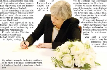  ?? — Reuters photo ?? May writes a message for the book of condolence­s for the victims of the attack on Manchester Arena, at Manchester Town Hall in Manchester.