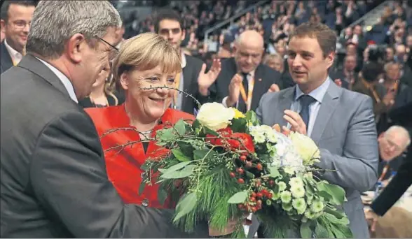  ?? KAI PFAFFENBAC­H / REUTERS ?? Angela Merkel recibiendo un ramo de flores tras ser reelegida como presidenta del partido, ayer en el congreso federal de la CDU en Essen