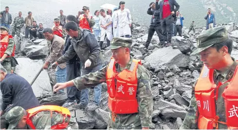  ??  ?? SEEKING SURVIVORS: Chinese military police and rescue workers comb through the rubble at the site of a landslide in Xinmo village of Mao County yesterday.