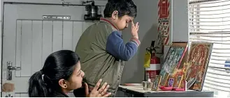  ??  ?? The Shah family like to start every day with a prayer, above left, and, centre, customers often want to know what Riddhi is cooking for her family at the back of the store. But there are often plenty of smiles out front with customers, right.