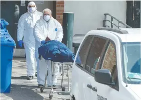  ?? RYAN REMIORZ / THE CANADIAN PRESS ?? Workers remove a body from a seniors residence in Montreal on Wednesday. Longterm care homes have been at the forefront of deaths due to COVID-19 in Canada.