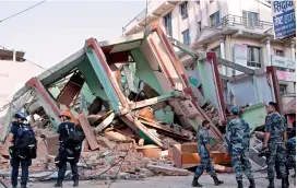  ?? — AP ?? Rescue workers stand beside a building that collapsed in an earthquake in Kathmandu, Nepal, on Tuesday. BELOW: An earthquake victim at the Teaching Hospital in Kathmandu.