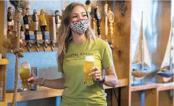  ?? MICHAEL LAUGHLIN/SOUTH FLORIDA SUN SENTINEL ?? Kiersten Miller, the bar manager at Coastal Karma Brewery in Lake Park serves customers on April 1. She started working in the brewery after the pandemic started last year.