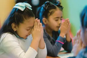  ?? JULIO CORTEZ/AP ?? Gaby Meza Rodriguez, 7, left, prays with other children at a Sunday school session Dec. 17 in Fort Morgan, Colo.