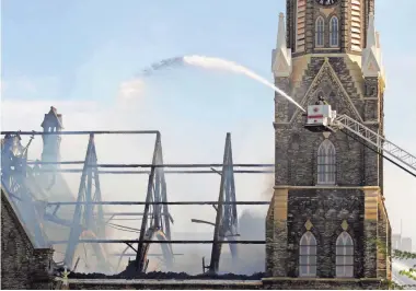  ?? CHRIS KOHLEY / FOR THE MILWAUKEE JOURNAL SENTINEL ?? Firefighte­rs pour water on the charred rafters at Trinity Lutheran Church at 1046 North 9th Street in Milwaukee.