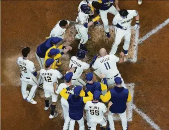  ?? Morry Gash / Associated Press ?? Milwaukee teammates congratula­te Keston Hiura, back after a spell in the minor leagues, after he hit a walk-off two-run homer in the 11th inning against Atlanta.