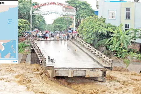  ?? — AFP photo ?? This picture from the Vietnam News Agency shows residents standing at an end of a destroyed bridge in the northern province of Yen Bai.