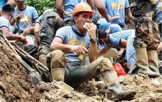  ?? Photo by Jean Nicole Cortes ?? LUNCH. A policeman takes a much needed lunch break as retrieval operations continue at the ground zero in level 070 Ucab, Itogon. Rescuers and volunteers said they need ready to eat food and a lot of water to function in the rigorous search and retrieval.