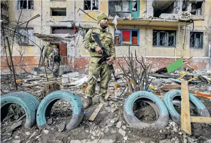  ?? Imago / Peter Kovalev ?? Ein Kämpfer vor einem zerstörten Wohnhaus in Mariupol im Osten der Ukraine.