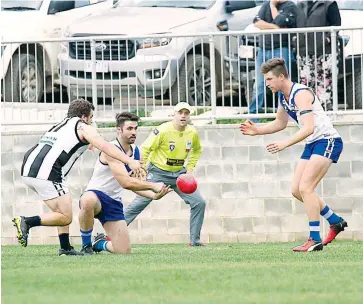  ??  ?? Tom Gill fires off the handball towards teammmate Tom Muir on the last line of defence as Neerim Neerim South sent a message to the rest of the EDFLwith a thrilling win over Poowong at home
Photos - MICHAEL ROBINSON