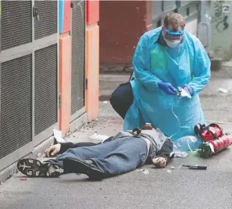  ?? JASON PAYNE ?? Ambulance paramedics help a man suffering a drug overdose in Vancouver's Downtown Eastside in May. Such gritty images have become commonplac­e, increasing­ly so during the COVID-19 pandemic.