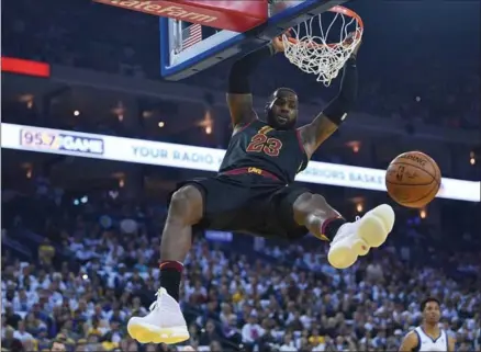  ?? THEARON W. HENDERSON, GETTY IMAGES ?? LeBron James of the Cleveland Cavaliers hangs on to the rim after a slam dunk against the Golden State Warriors. The Warriors won, 99-92.