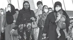  ??  ?? Families evacuated from Kabul, Afghanista­n, walk through the terminal before boarding a bus after they arrived at Washington Dulles Internatio­nal Airport, in Chantilly, Virginia, on Thursday.