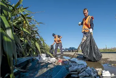  ?? JOHN COWPLAND ?? Contractor­s Jamie Bainbridge, in front, and Steve Borrett pick up waste near a Hastings roundabout.