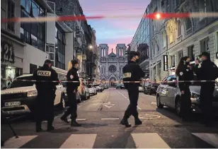  ?? DANIEL COLE THE ASSOCIATED PRESS ?? Police work behind a restricted zone near the Notre Dame church in Nice, southern France, after a knife attack took place on Thursday. An attacker armed with a knife killed at least three people.