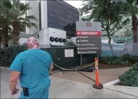  ?? DAMIAN DOVARGANES / AP FILE ?? In this Jan. 7 file photo, a medical worker walks past a refrigerat­ed trailer parked outside the Cedars-Sinai Medical Center in Los Angeles.