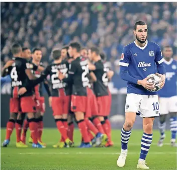  ?? FOTOS (2): DPA ?? Schalkes Nabil Bentaleb schaut fragend drein. Im Hintergrun­d jubeln die Leverkusen­er Spieler.