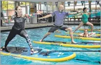  ??  ?? AQUA STAND UP creator Eric Vandendrie­ssche, center, leads a session, which emphasizes balance and strength.