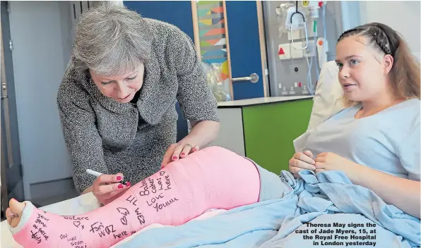  ??  ?? Theresa May signs the cast of Jade Myers, 15, at the Royal Free Hospital in London yesterday