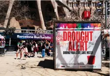  ?? ?? A couple uses a selfie stick to take a picture next to a banner warning tourists on drought alert in Catalonia, near Sagrada Familia basilica in Barcelona.