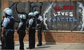  ?? Photograph: Pat Nabong/AP ?? Police officers stand beside a mural for George Floyd in the neighborho­od of Bronzevill­e, in Chicago, during an anti-police brutality protest.