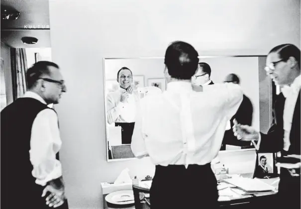  ??  ?? Spieglein, Spieglein an der Wand: Sinatra bindet sich die Fliege, für seinen abendliche­n Auftritt bei der Amtseinfüh­rungsparty für John F. Kennedy wird er gut aussehen. Seine Adjutanten im Statler Hilton stehen ihm helfend zur Seite, im Jänner 1961 in New York