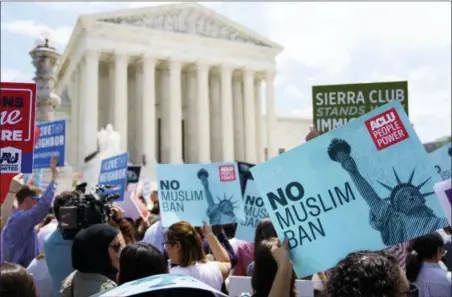  ?? CAROLYN KASTER — THE ASSOCIATED PRESS ?? Protesters hold up signs and call out against the Supreme Court ruling upholding President Donald Trump’s travel ban Tuesday outside the Supreme Court in Washington.