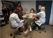  ?? AP PHOTO/VIRGINIA MAYO ?? Belgium’s Queen Mathilde, fourth left, speaks with a volunteer, second right, as she receives an injection at the Center for the Evaluation of Vaccinatio­ns (CEV) in Antwerp, Belgium, Wednesday.