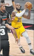  ?? Darren Abate The Associated Press ?? Lakers forward Lebron James drives to the basket against Spurs forwards Rudy Gay and Keldon Johnson in the second half of Los Angeles’ 109-103 win Friday at the AT&T Center. James had 26 points.