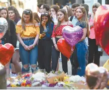  ?? AFP-Yonhap ?? People pay their respects as they look at flowers and balloons left in central Manchester Tuesday, the one year anniversar­y of the deadly attack at Manchester Arena.