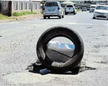  ?? MJEKULA Picture: LUVUYO ?? Mlungisi resident Nombulelo ‘Sis Tsetse’ Nqayi this week placed an old tyre and polystyren­e over a pothole in the middle of Victoria Road ‘to save lives’