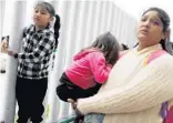  ?? MARIO TAMA/GETTY IMAGES ?? A migrant mother in Tijuana, Mexico, waits with her two daughters on their way to the port of entry to ask for asylum in the U.S. on Thursday.