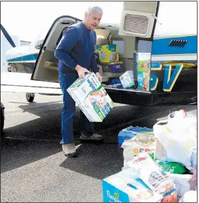  ?? AP/NATI HARNIK ?? Pilot Herb Johansen of Bennington, Neb., unloads supplies he volunteere­d to fly into the Fremont, Neb., airport on Monday. Johansen is among several pilots who volunteere­d to fly supplies into and shuttle residents in and out of Fremont, which has been cut off by flooding from the Platte River.