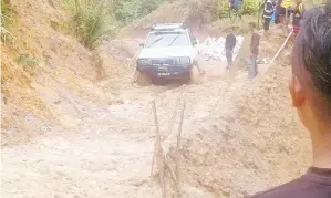  ??  ?? KEADAAN jalan yang licin dan berlumpur menyukarka­n kenderaan melaluinya.