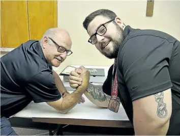  ?? CATHY PELLETIER/SPECIAL TO POSTMEDIA NEWS ?? Thorold Mayor Ted Luciani, left, tries his hand at arm wrestling after recognizin­g Joshua D'Erchia for winning medals at the national and world powerlifti­ng championsh­ips.