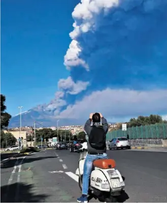  ?? EPA ?? Ein Mann fotografie­rt am 24. Dezember von Catania aus den von Rauchwolke­n umhüllten Ätna.