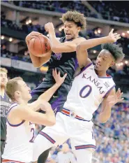  ?? CHARLIE RIEDEL/ASSOCIATED PRESS ?? Washington’s Matisse Thybulle, center, beats Kansas’ Clay Young, left, and Marcus Garrett (0) to a rebound during Wednesday night’s game. The Huskies defeated the Jayhawks 74-65.