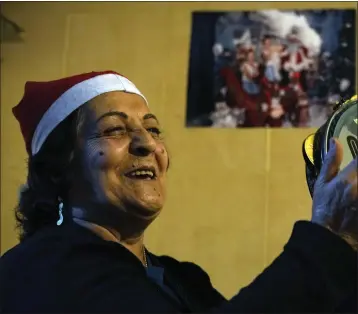  ?? BILAL HUSSEIN — THE ASSOCIATED PRESS ?? Palestinia­n Afife Atieh plays the tambourine during a community Christmas dinner for elderly residents at the only majority-Christian Palestinia­n refugee camp, in Dbayeh, north of Beirut, Lebanon, on Wednesday.