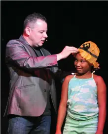  ??  ?? At top, magician Scott Davis has Austin Davis of Beckville, Texas, read prediction­s he made, and, at bottom, he places a hat he made appear on Mykhael King, 9, of Pine Bluff, as she assists him during the show.