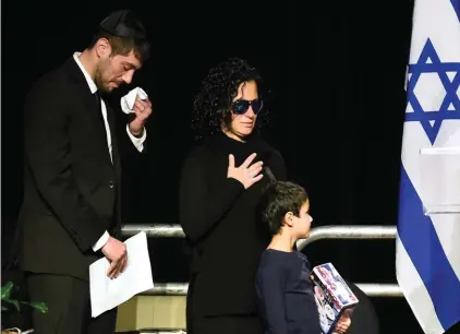  ??  ?? Jonathon Sherman wipes his tears as he and his sister Lauren walk to the stage during a memorial service