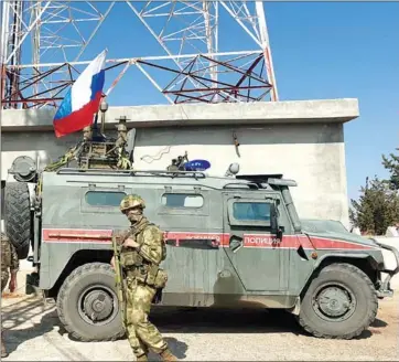  ?? AFP ?? Russian soldiers walk past an armoured vehicle in the northeaste­rn Syrian city of Kobane along the border with Turkey on Wednesday.