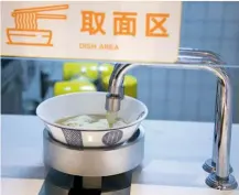  ??  ?? Un cliente usa el móvil para pagar la cuenta en el restaurant­e Hongqiao Artificial Intelligen­ce, de Shanghái (China). Allí todos los platos son preparados –abajo– por aparatos y brazos robóticos manejados por una inteligenc­ia artificial capaz también de sugerir menús, que se muestran en pantallas táctiles.