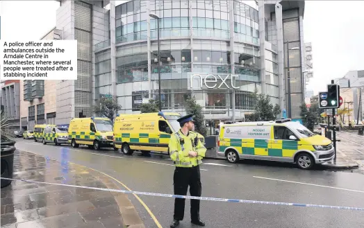  ??  ?? A police officer and ambulances outside the Arndale Centre in Manchester, where several people were treated after a stabbing incident