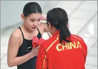  ?? HE CHANGSHAN / XINHUA ?? Zhang Jiaqi of China consults with her coach on her way to winning the women’s 10m platform at the FINA Diving World Series at the Water Cube in Beijing on Sunday.