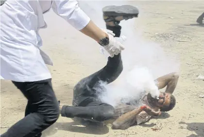  ??  ?? FLASHPOINT: A Palestinia­n medic rushes to help a protester who was shot in the face with a tear gas canister fired by Israeli troops near the Gaza Strip’s border with Israel, east of Khan Younis, in the Gaza Strip, on Friday.