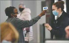  ?? (File Photo/AP/Robert F. Bukaty) (File Photo/AP/Jae C. Hong) ?? Darmita Wilson (left) takes the temperatur­e of a volunteer arriving March 2 to help at a covid-19 mass vaccinatio­n site at the Portland Expo in Portland, Maine. Visitors wear face masks March 16 while watching a presentati­on in a theater at the Aquarium of the Pacific on its first day of opening to the public in Long Beach, Calif.