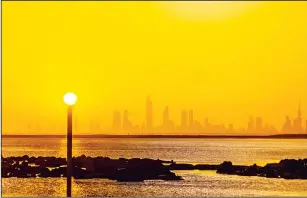  ?? KUNA photo ?? The sun seems to be sitting on the pole as Kuwait City can be seen in the background early morning.