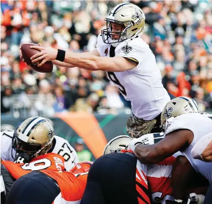  ?? FRaNK VICTORES/THE ASSOCIATED PRESS ?? New Orleans Saints quarterbac­k Drew Brees goes airborne to score a touchdown in his team’s 51-14 victory over the Bengals Sunday in Cincinnati. The Saints won their eighth straight game and Brees passed Brett Favre for second in career touchdown passes.