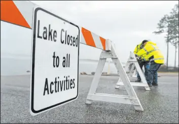  ?? Jason Fochtman The Associated Press ?? Workers put up barricades and signs at the boat ramp entrance to Lake Conroe on Wednesday in Conroe, Texas. The region was hit with its third day of widespread rainfall.